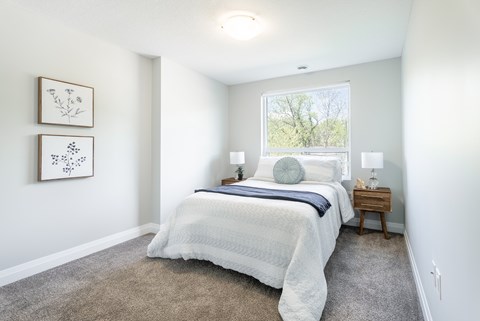 A bedroom with a large bed and two pictures on the wall.