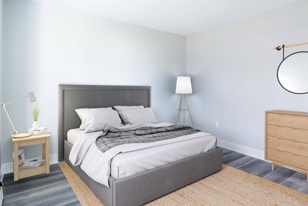 A bedroom with a large bed and a lamp on a side table.