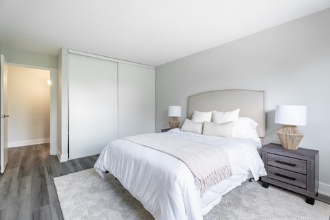 A bedroom with a large bed and a nightstand with a lamp.