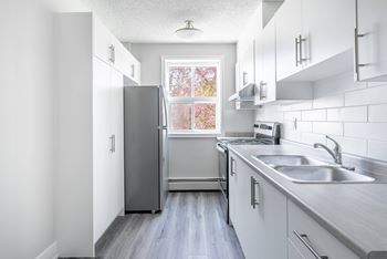 a white kitchen with stainless steel appliances and a window