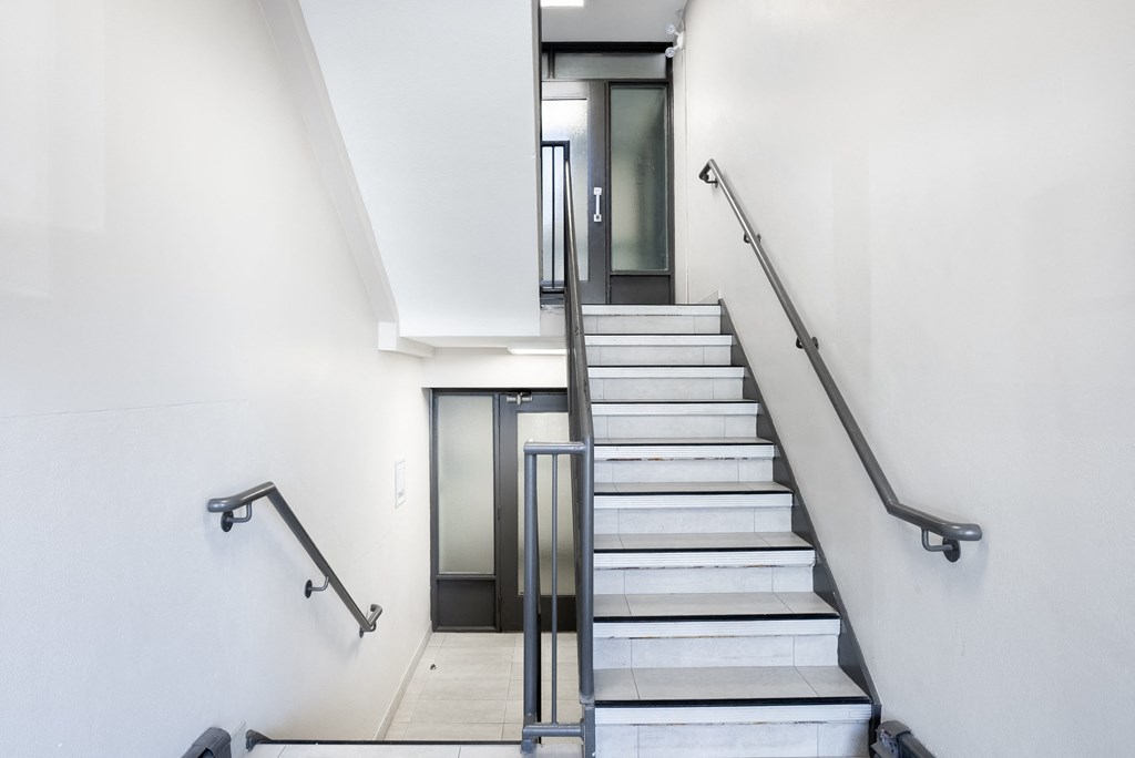 Interior Oakland staircase with a metal railing and a glass door at the top.