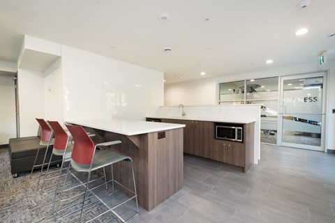 a kitchen with white countertops and a wooden island with four chairs