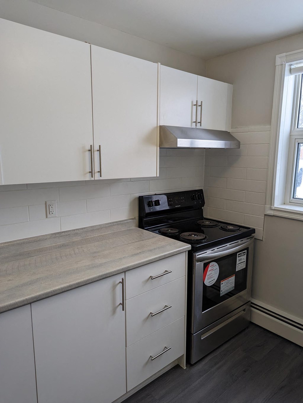 an empty kitchen with white cabinets and a black stove