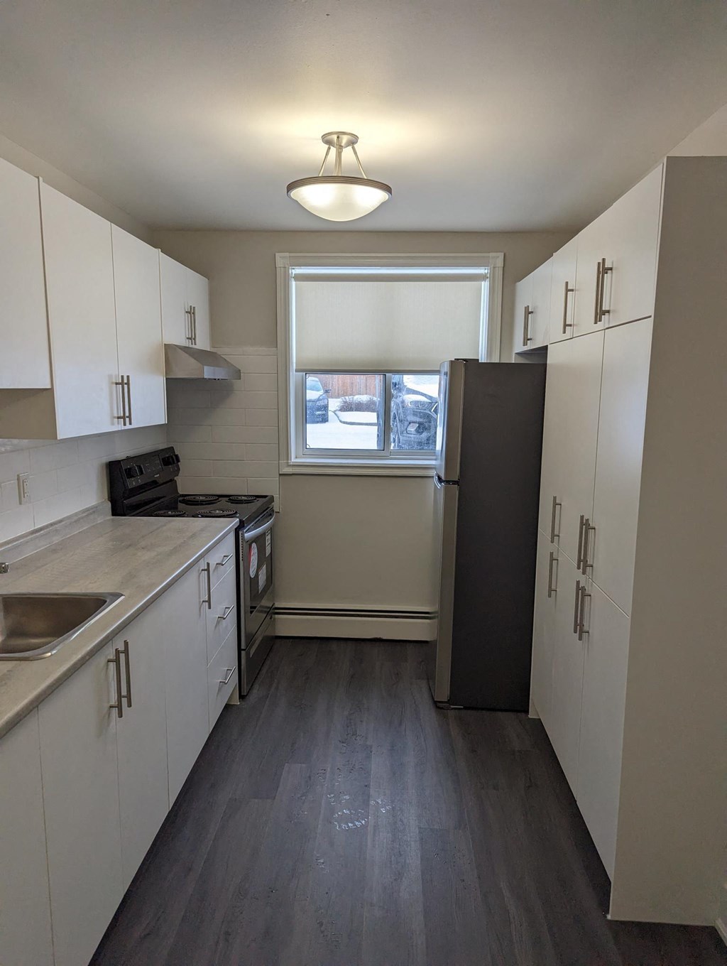 a small kitchen with white cabinets and a window