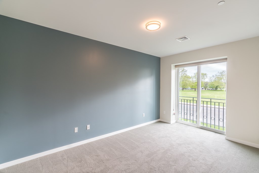 an empty room with a sliding glass door and a view of a golf course