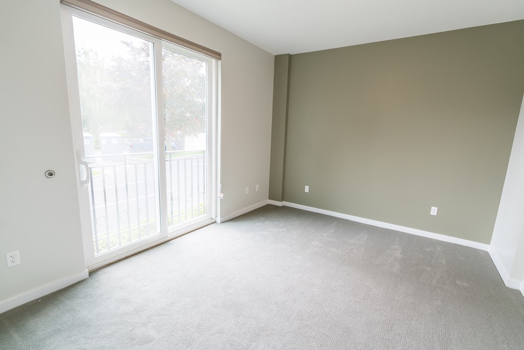 an empty bedroom with a large window and a balcony