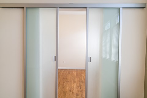 a sliding glass door leading into an empty room with a hardwood floor