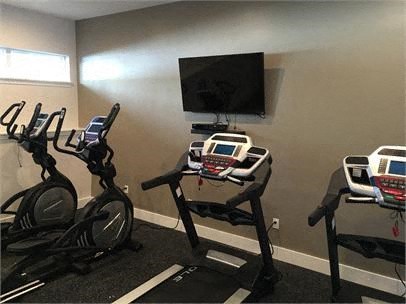 a room filled with lots of exercise equipment and a flat screen tv