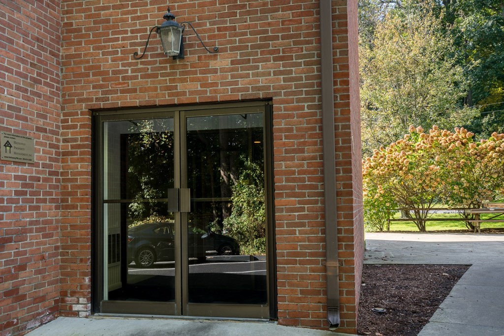 a brick building with a glass door with a car reflected in it