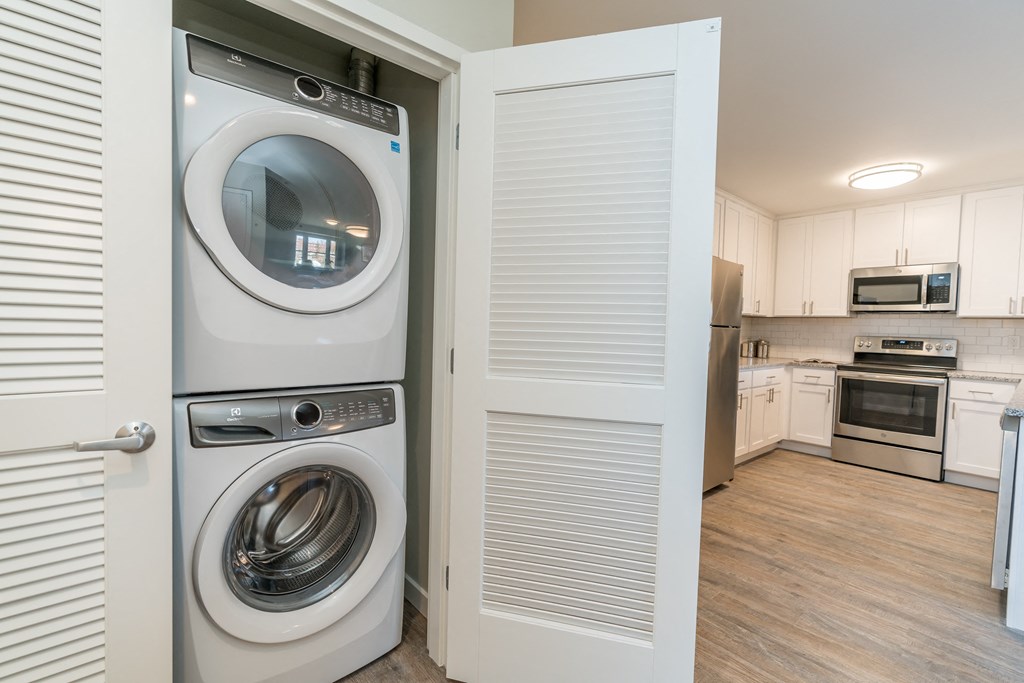a washer and dryer in a laundry room with a kitchen in the background