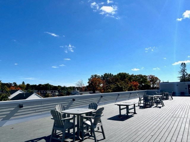 a roof deck with tables and chairs and a blue sky