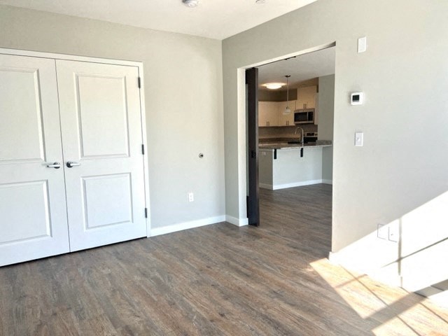 an empty living room with a kitchen in the background