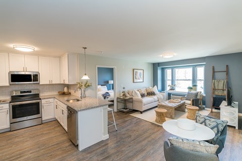a kitchen and living room with white cabinets and a counter top