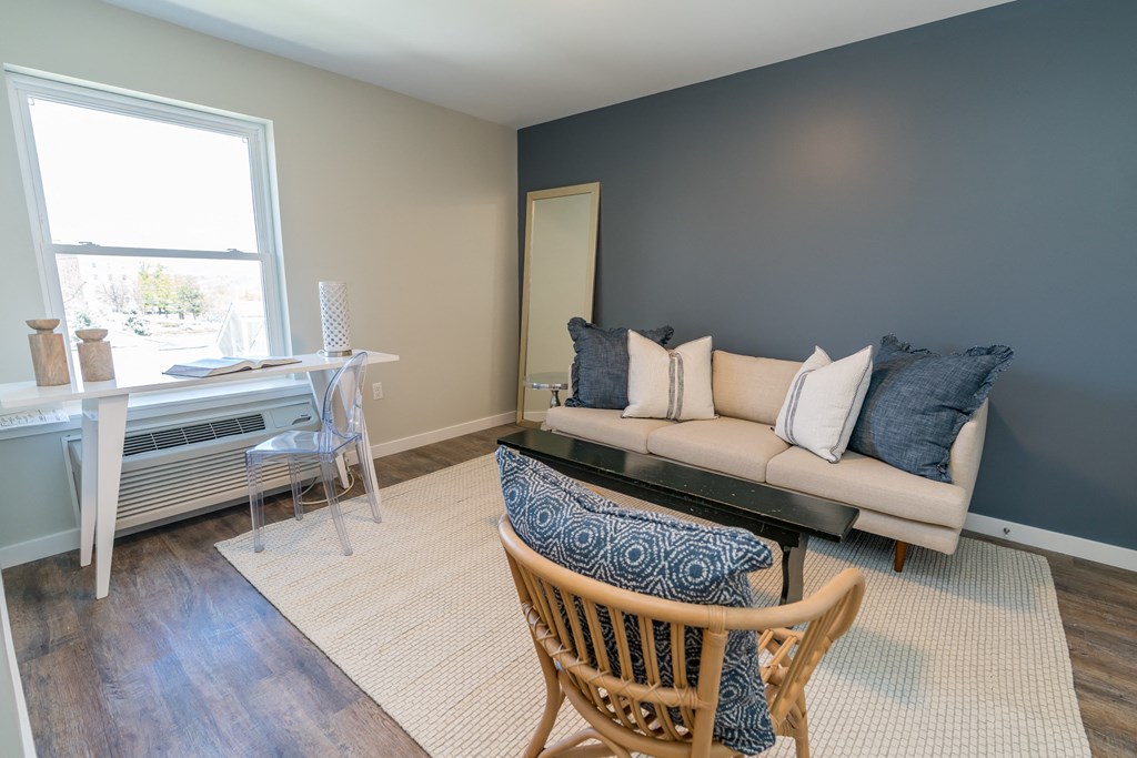 a living room with a couch chair and desk in front of a window