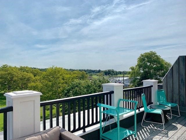 a balcony with green chairs and a view of a river