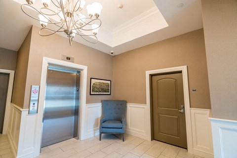 a hallway with a blue chair and a chandelier