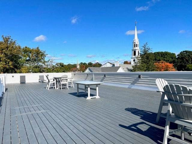 a roof deck with a table and chairs and a church in the background