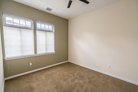 a bedroom with two windows and a ceiling fan