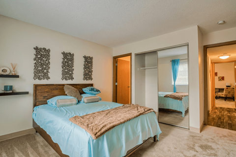 A bedroom with a bed, a mirror, and a nightstand.