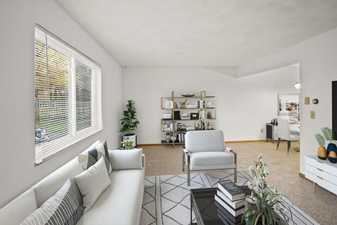 A living room with a white sofa, a chair, a coffee table, and a bookshelf.