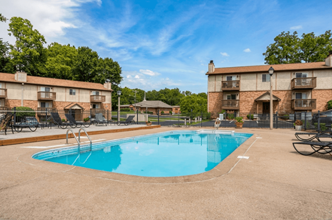 A swimming pool surrounded by chairs and buildings.