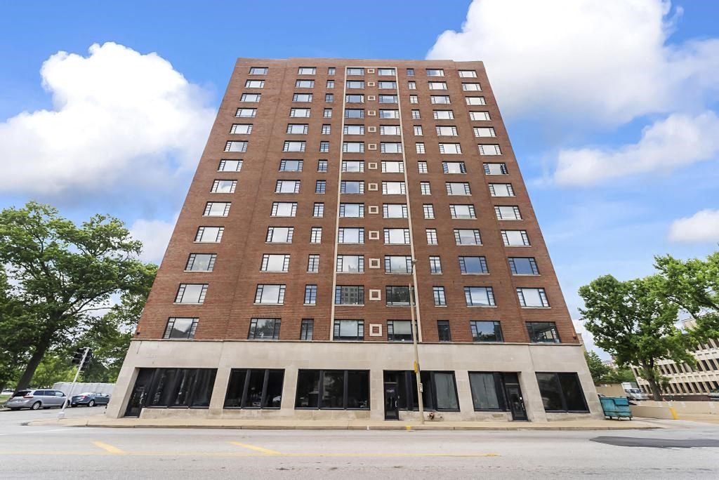 a tall building with many windows and a cloudy blue sky in the background