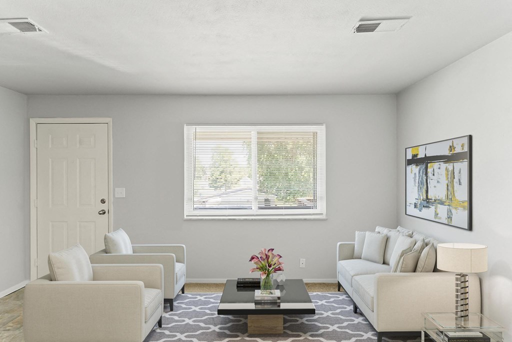 a living room with white couches and chairs and a coffee table with a flower vase