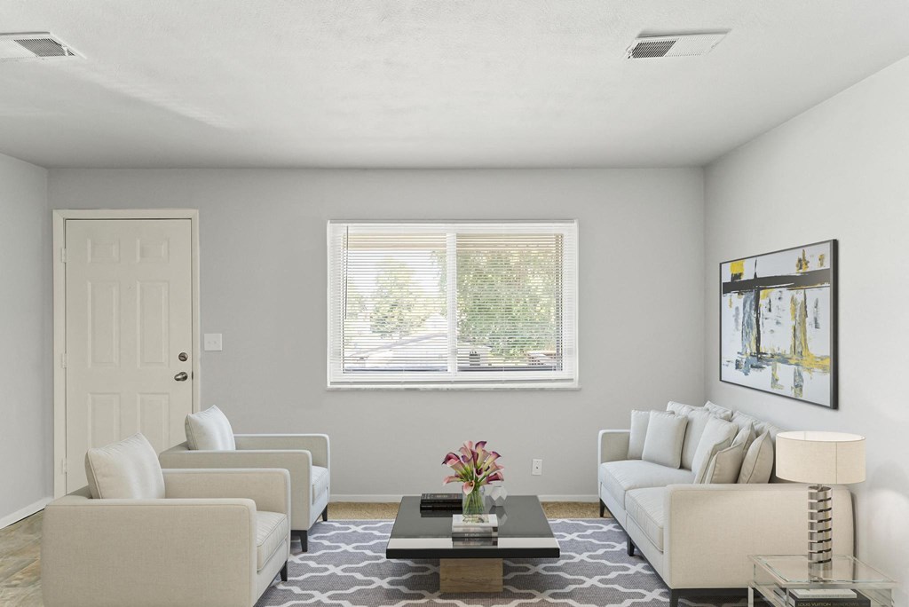 a living room with white couches and chairs and a coffee table with a flower vase