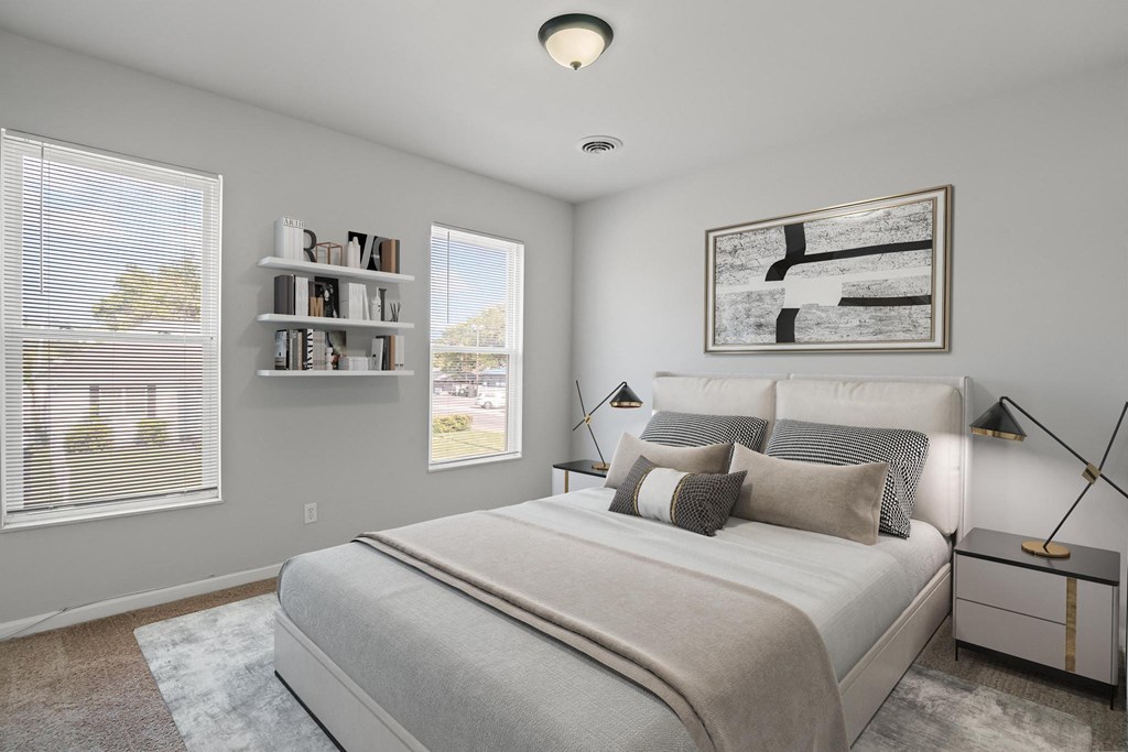 a bedroom with a large bed and two windows