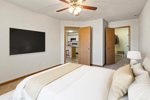 A bedroom with a large bed and a flat screen TV on the wall.