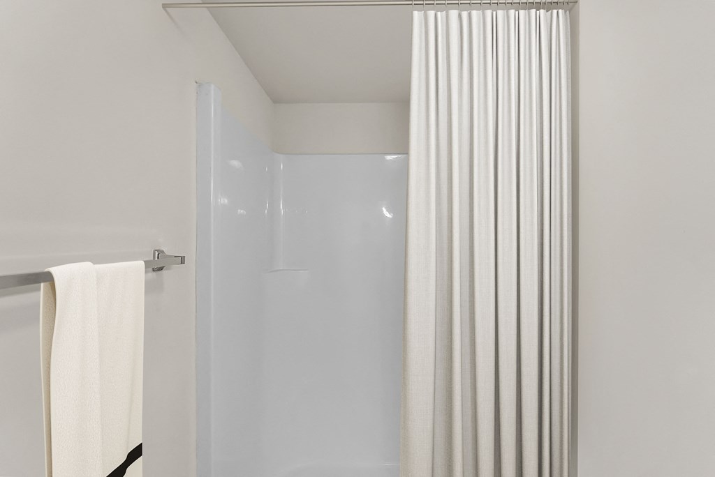 a bathroom with a shower and a white shower curtain
