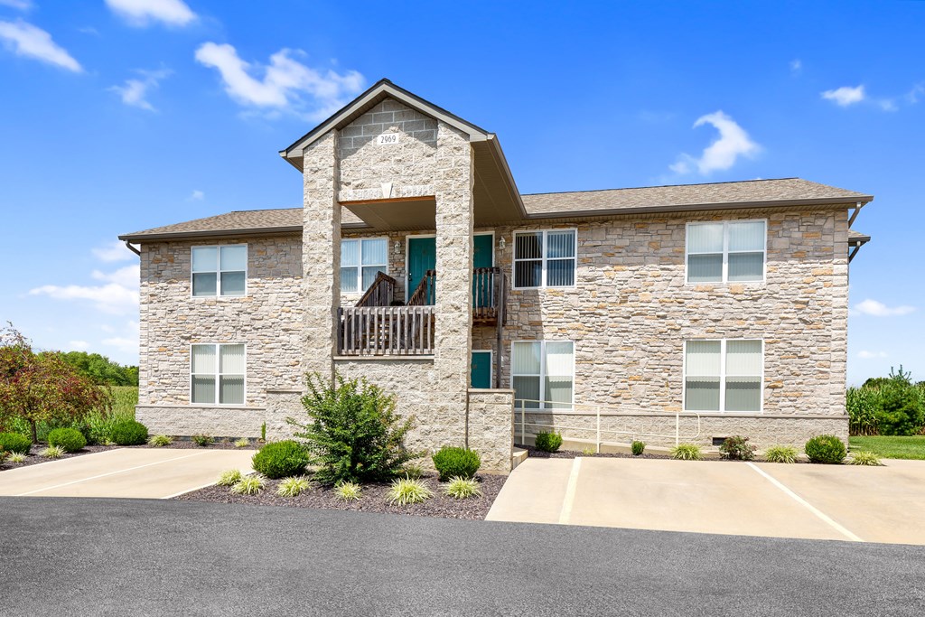a large stone house with a balcony and a parking lot