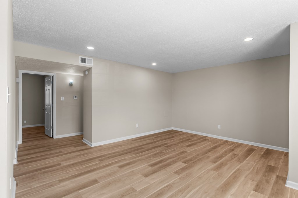an empty living room with wood flooring and grey walls