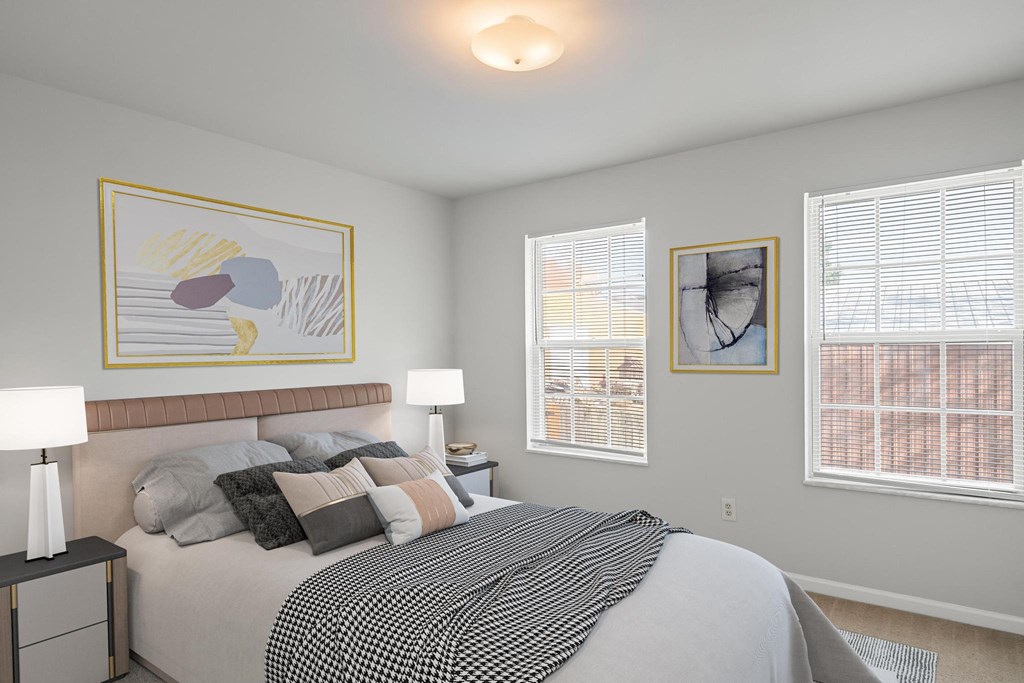 a bedroom with a large bed and two windows