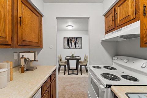 a kitchen with a stove and a dining room with a table and chairs