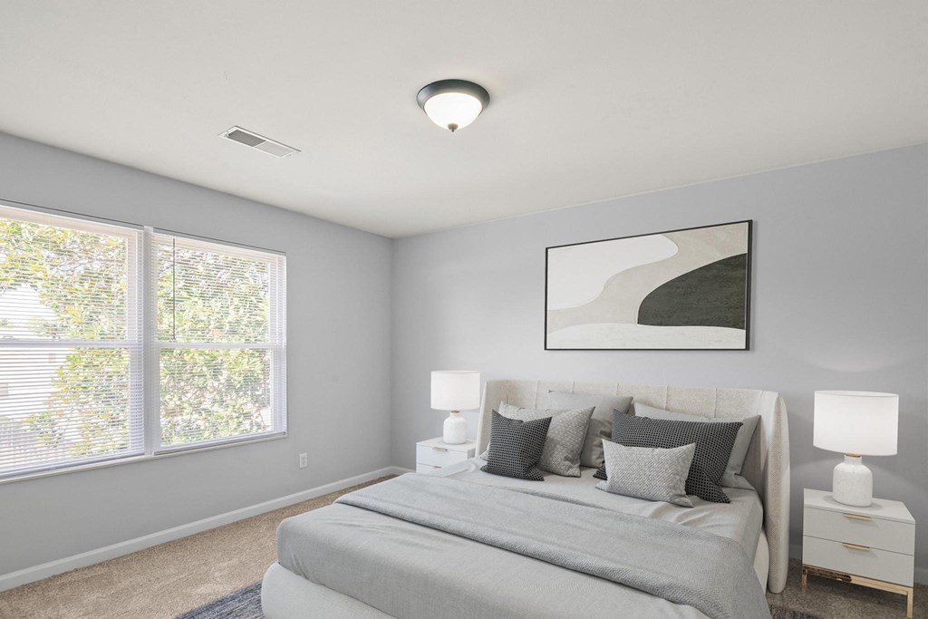 a bedroom with a large bed and two windows