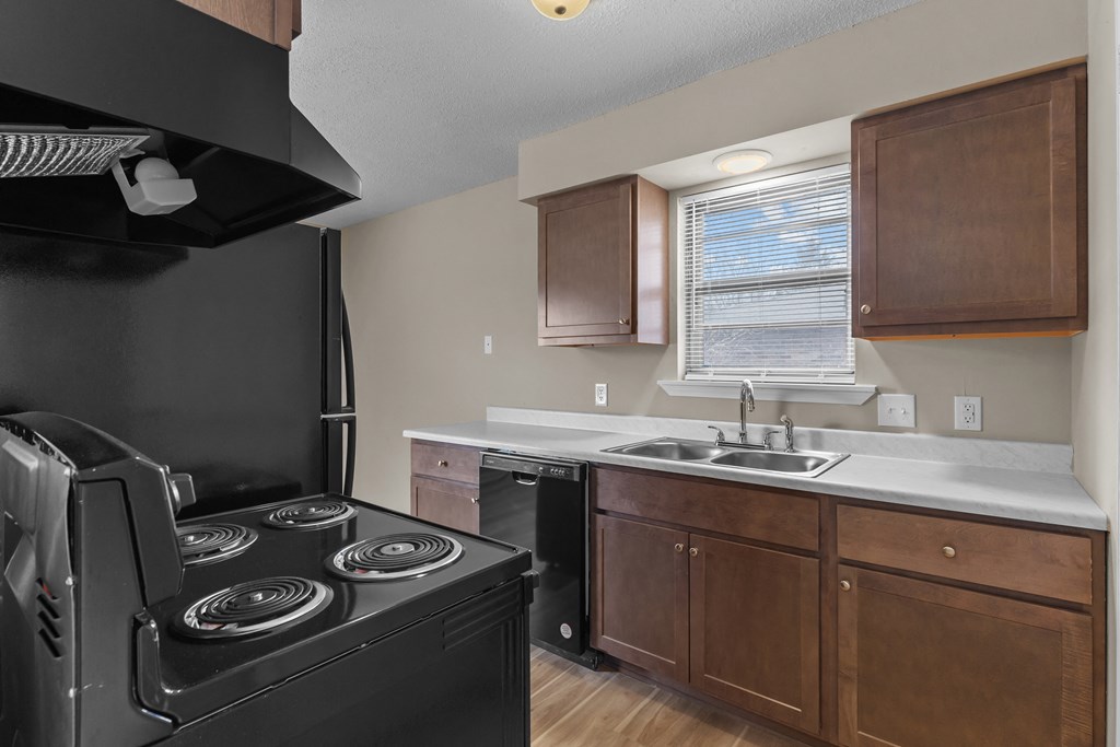 an empty kitchen with black appliances and wooden cabinets
