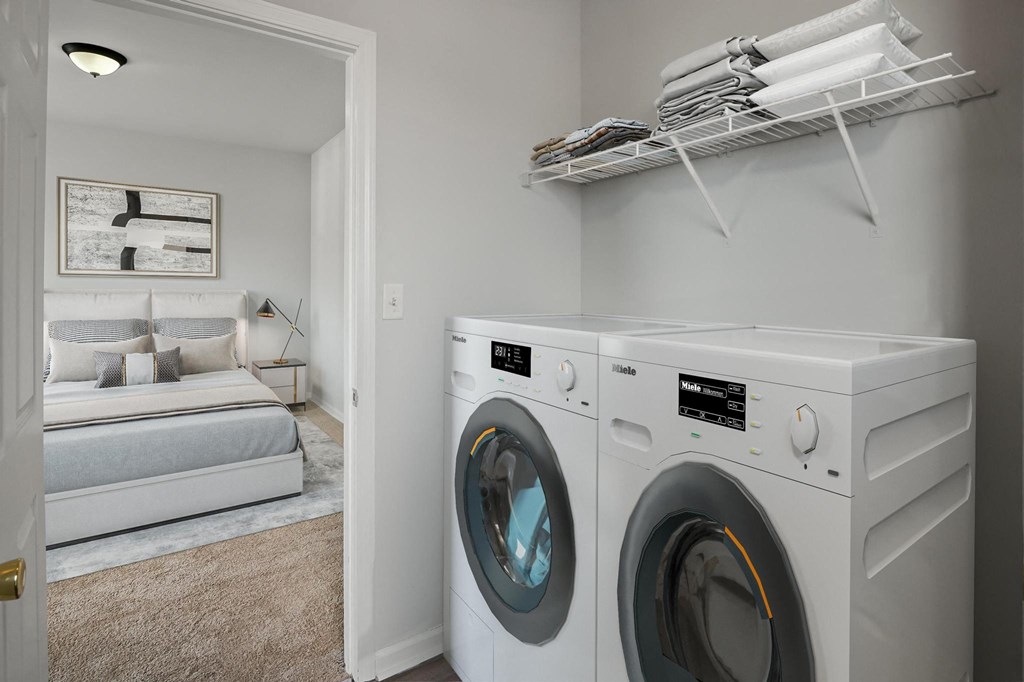 a washer and dryer in a laundry room with a bed in the background