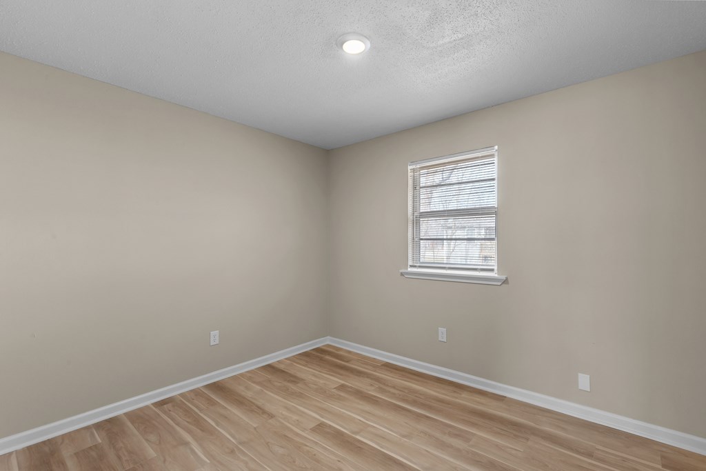 an empty room with wood floors and a window