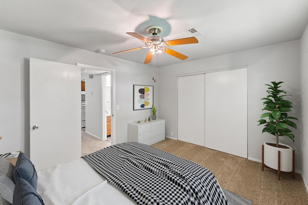 a bedroom with a ceiling fan and white walls