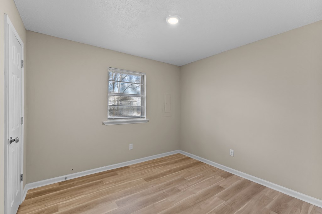 an empty room with wooden floors and a window