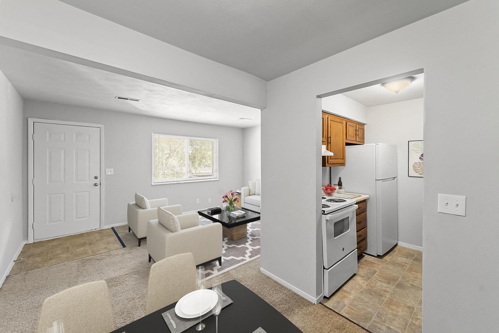 a living room with a table and chairs and a kitchen with a refrigerator and stove