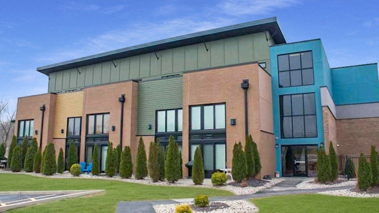 the front of a building with windows and a green roof