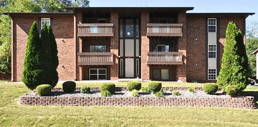 a large brick apartment building with a garden in front of it