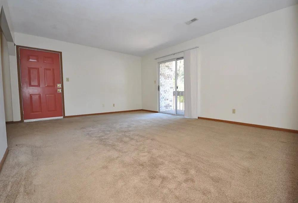 an empty living room with a red door