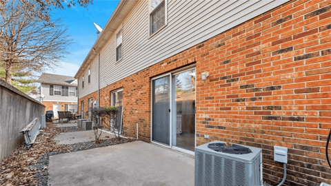 A brick wall with a sliding glass door and a wall-mounted air conditioning unit.