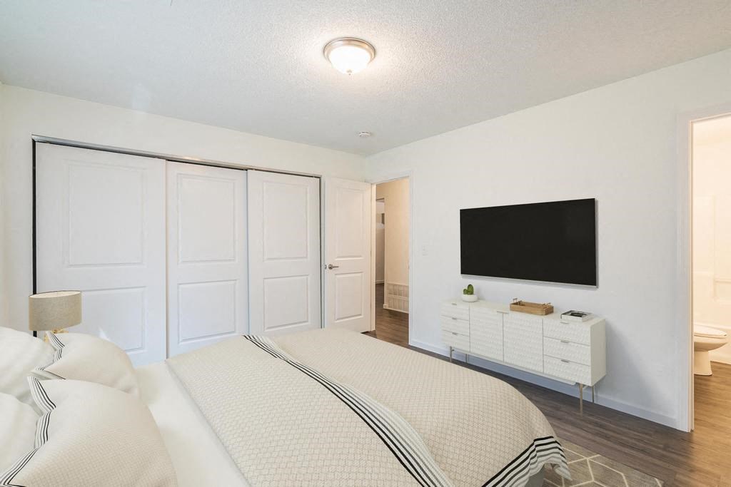 a bedroom with a bed and a television on the wall