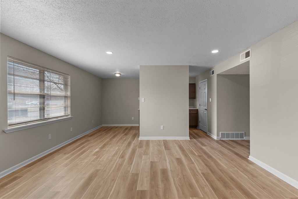 an empty living room with a window and wood flooring