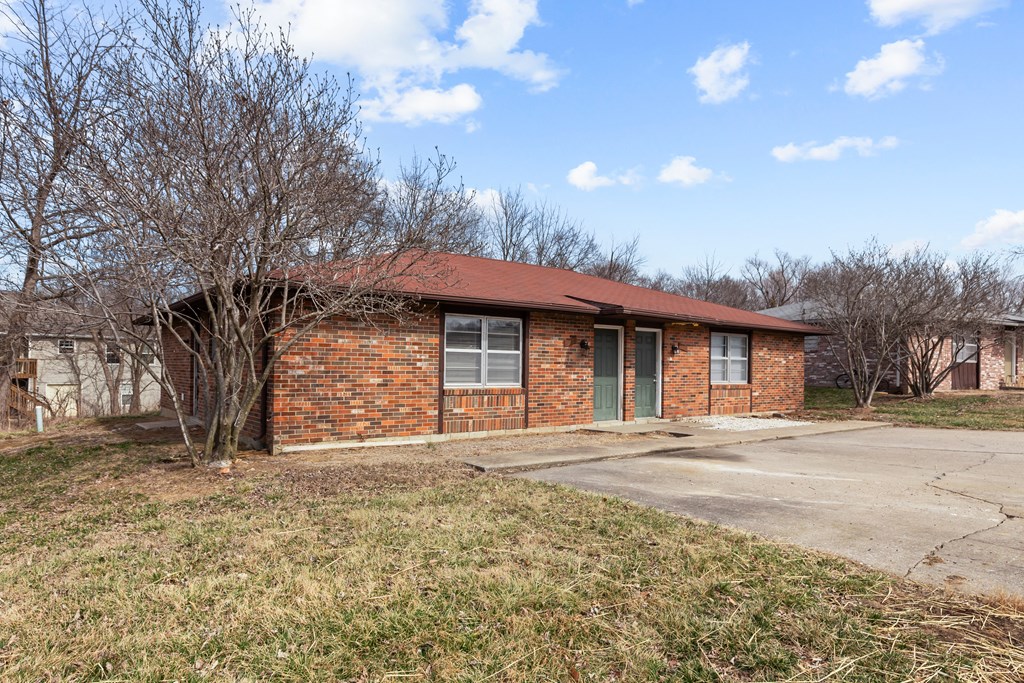 a small brick house with a sidewalk in front of it