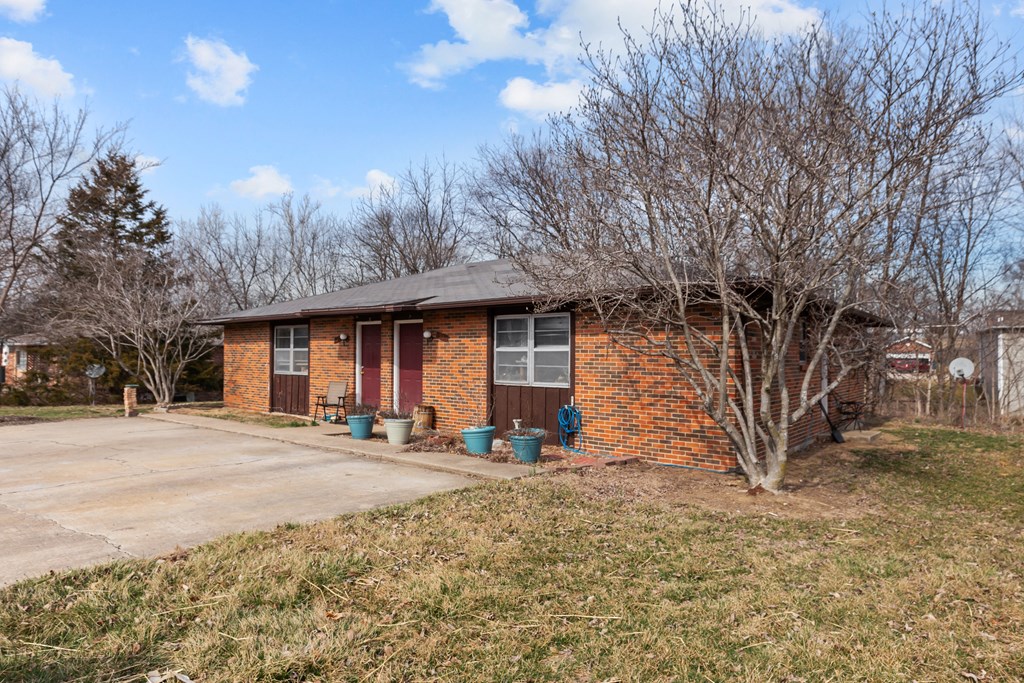 a small brick house with a tree in front of it